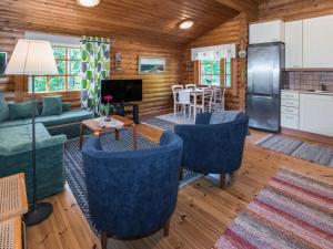 ein Wohnzimmer mit einem Sofa und Stühlen sowie eine Küche in der Unterkunft Holiday Home Kiimalammi by Interhome in Niittymaa
