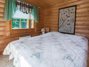 ein Schlafzimmer mit einem Bett in einer Blockhütte in der Unterkunft Holiday Home Kiimalammi by Interhome in Niittymaa + 11 Fotos