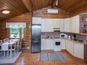 eine Küche mit weißen Schränken und einem Tisch in einer Hütte in der Unterkunft Holiday Home Kiimalammi by Interhome in Niittymaa