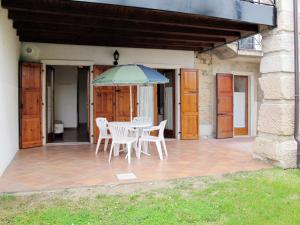 eine Terrasse mit einem Tisch, Stühlen und einem Sonnenschirm in der Unterkunft Apartment Ca' Pignoi-3 by Interhome in Garda