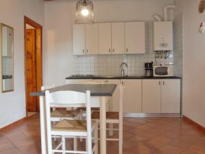 eine Küche mit weißen Schränken sowie einem Tisch und Stühlen in der Unterkunft Apartment Ca' Pignoi-3 by Interhome in Garda