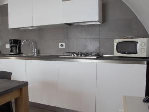 cocina con armarios blancos y microondas en la encimera en Apartment Ca' Pignoi-2 by Interhome, en Garda