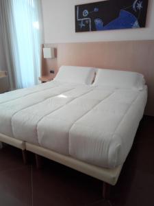 un grande letto bianco in una camera da letto di Hotel Chiaraluna a Civitanova Marche