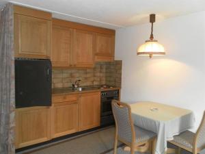 eine Küche mit Holzschränken und einem Tisch mit Stühlen in der Unterkunft Apartment Ammerten A17 by Interhome in Lenk im Simmental