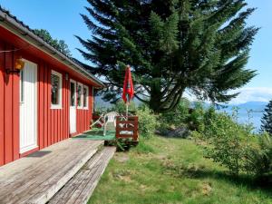 ein rotes Haus mit einer Holzterrasse neben einem Baum in der Unterkunft Chalet Haugen - FJS024 by Interhome in Balestrand