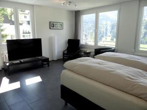 a bedroom with two beds and a flat screen tv at Apartment Barbara Ost by Interhome in Engelberg