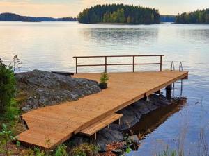 a wooden dock with a bench on top of a lake at Holiday Home Rihka by Interhome in Luopioinen
