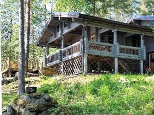 a large wooden house with a large deck in the woods at Holiday Home Rihka by Interhome in Luopioinen