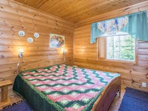 ein Schlafzimmer mit einem Bett in einer Blockhütte in der Unterkunft Holiday Home Polaria by Interhome in Niittymaa