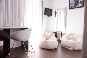 a living room with two white chairs and a television at THE SILK Hotel in Paralia Katerinis