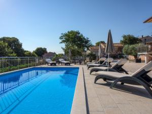 a swimming pool with lounge chairs and umbrellas at Holiday Home Legović by Interhome in Kaštelir +28 photos