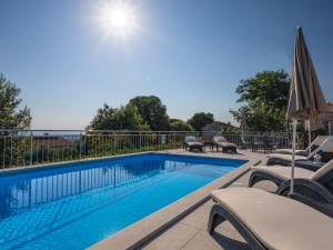 a swimming pool with chairs and an umbrella at Holiday Home Legović by Interhome in Kaštelir