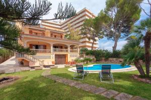 ein Haus mit einem Pool und zwei Stühlen im Hof in der Unterkunft Villa Tossals in El Arenal