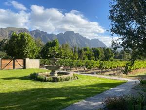 a garden with a fountain in the middle of a field at Franschhoek Rose Cottages in Franschhoek