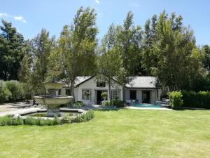 a house with a fountain in the yard at Franschhoek Rose Cottages in Franschhoek
