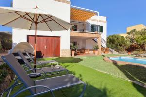 een tuin met stoelen en een parasol en een zwembad bij Villa Son Veri Miramar in El Arenal