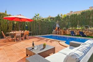 a patio with a table and an umbrella next to a pool at Villa Ocells II in Puigderrós