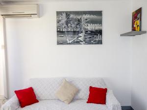 a living room with a white couch with red pillows at Studio Le Grand Galion-3 by Interhome in Le Grau-du-Roi