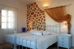 a bedroom with a bed with a stone wall at Chora Resort Hotel & Spa in Chora Folegandros