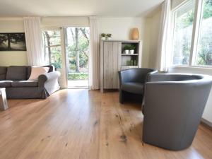 ein Wohnzimmer mit Holzböden, einem Sofa und Stühlen in der Unterkunft Chalet Oosterduinen by Interhome in Norg