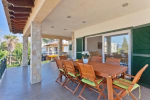 uma sala de jantar com uma mesa de madeira e cadeiras numa varanda em Bellavista em Cala Blava