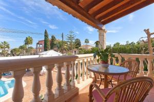 balcón con mesa, sillas y piscina en Villa Las Palmeras, en Urbanización Ses Palmeres