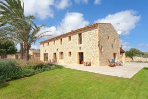 a large stone building with a palm tree and a yard at Sa Murtera in Manacor