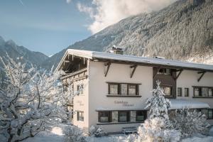 a building in the snow with mountains in the background at Gästehaus Oblasser in Mayrhofen