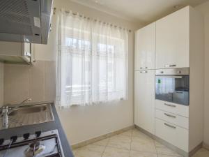 a kitchen with white cabinets and a sink and a window at Apartment Aurora by Interhome in Buzet