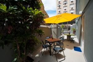 einen Balkon mit einem Tisch, Stühlen und einem gelben Regenschirm in der Unterkunft Gaia Hostel in Rio de Janeiro
