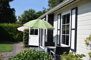 una mesa con una sombrilla verde en el lateral de una casa en 2 2-persoons Hotel kamer, en Voorthuizen