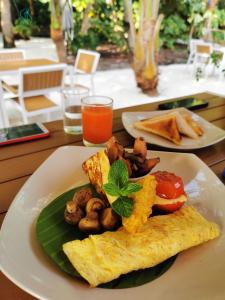 une assiette de nourriture avec des œufs et des champignons sur une table dans l'établissement Village Hideaways & Spas, à Fulhadhoo