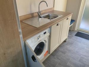 a kitchen with a sink and a washing machine at Clouded Yellow - beautiful modern lodge Kippford in Dalbeattie