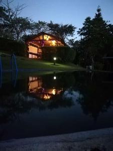 einem beleuchteten Gebäude mit Spiegelung in einem Teich in der Unterkunft Pochote Lodge in Guayabos