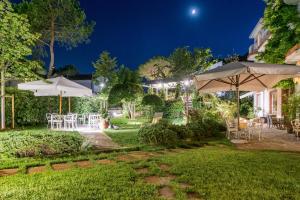 ミラノ・マリッティマにあるVilla Arizonaの夜のテーブルと傘を用意した庭園