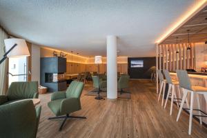 salon z zielonymi krzesłami i kuchnią w obiekcie Hotel Lindnerhof w mieście San Lorenzo di Sebato