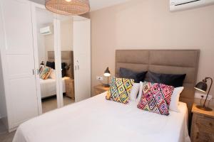 a bedroom with a white bed with pillows and a mirror at Casa Calma Moraira in Moraira +37 photos