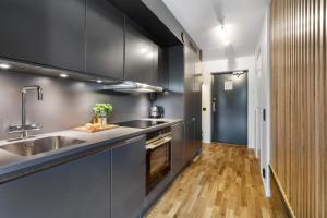 a kitchen with black cabinets and a sink at HOOM Home & Hotel Sollentuna in Sollentuna