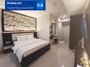 1 dormitorio con 1 cama con una pintura en la pared en Apartemen Grand Kamala Lagoon Studio By Bonzela Property en Bekasi