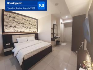 a bedroom with a bed with a painting on the wall at Apartemen Grand Kamala Lagoon Studio By Bonzela Property in Bekasi