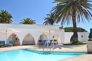 a pool with chairs and umbrellas next to a building at Casa Três Palmeiras in Portimão