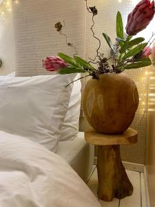 a vase with flowers on a wooden table next to a bed at Casa De Palmas in Alkmaar