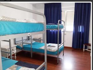 a room with three bunk beds and blue curtains at Albergue Pensión Flavia in Padrón