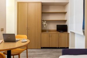 Cette chambre dispose d'une télévision et d'une table avec un ordinateur portable. dans l'établissement Residence Portello, à Milan