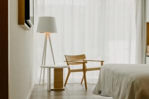 a bedroom with a chair and a lamp next to a bed at Instants Boutique Hotel in Cambrils