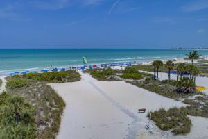 a beach with a bench and umbrellas and the ocean at Siesta Sands Beach Resort 4th Floor with Elevator in Sarasota