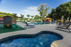 uma piscina com cadeiras, uma mesa e um parque infantil em Cataratas Park Hotel e Eventos em Foz do Iguaçu