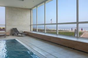 a swimming pool in a building with a view of the ocean at Christiansen im Panoramahaus Duhnen in Cuxhaven