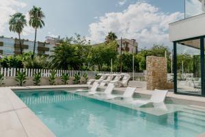 uma piscina com espreguiçadeiras brancas e uma piscina em Instants Boutique Hotel - Adults Only em Cambrils