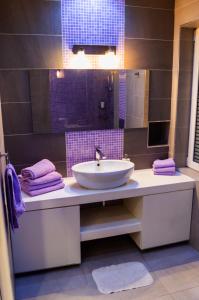 y baño con lavabo y azulejos púrpura. en Terranova Apartment (city central), en Belgrado